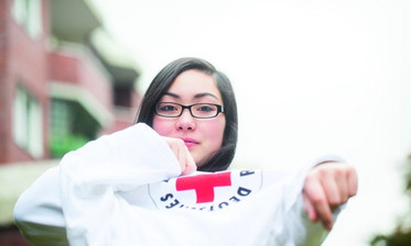 Junge Frau zieht sich ein T-Shirt mit DRK - Logo über