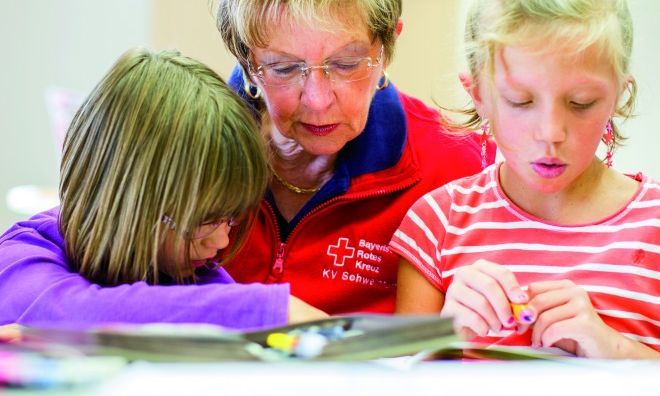 Ältere Freiwillige unterstützt Kinder bei den Hausaufgaben