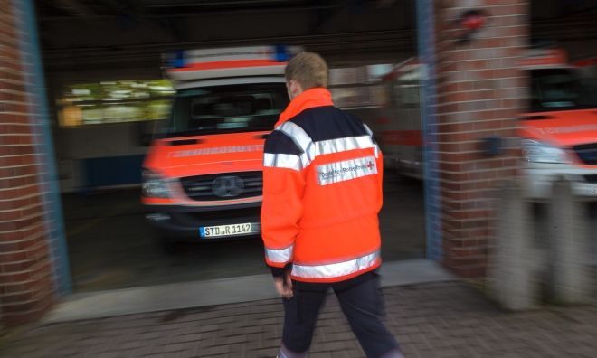 Ein Freiwilliger in DRK-Kleidung geht auf einen Rettungswagen zu